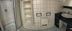 Salle de bain équipée avec douche, lavabo et espaces de rangement fonctionnels
